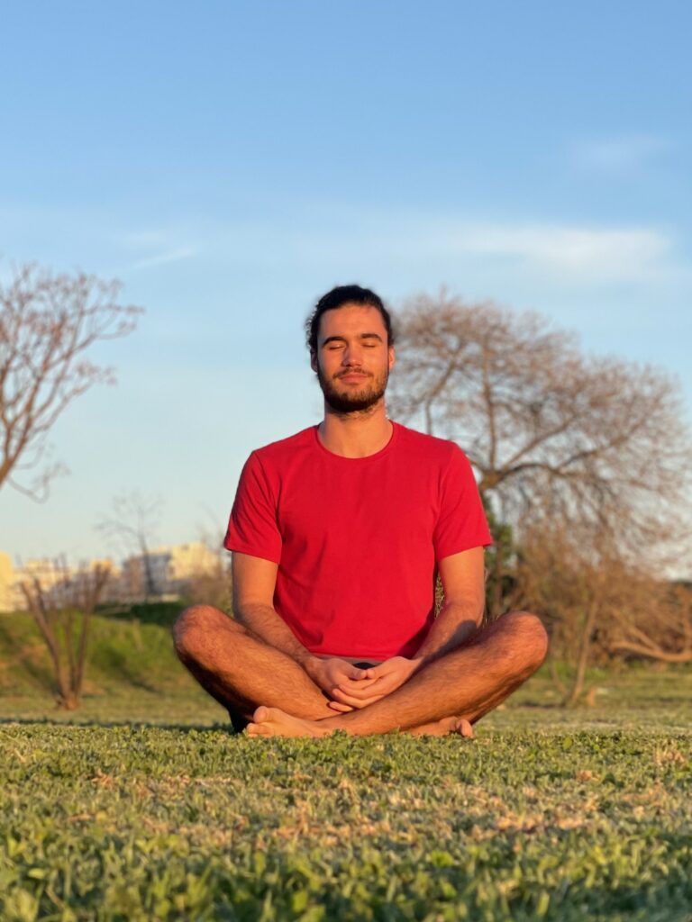 Befriend Your Emotions Dr. Filipe Rocha meditating cross-legged on the grass in a park, eyes closed